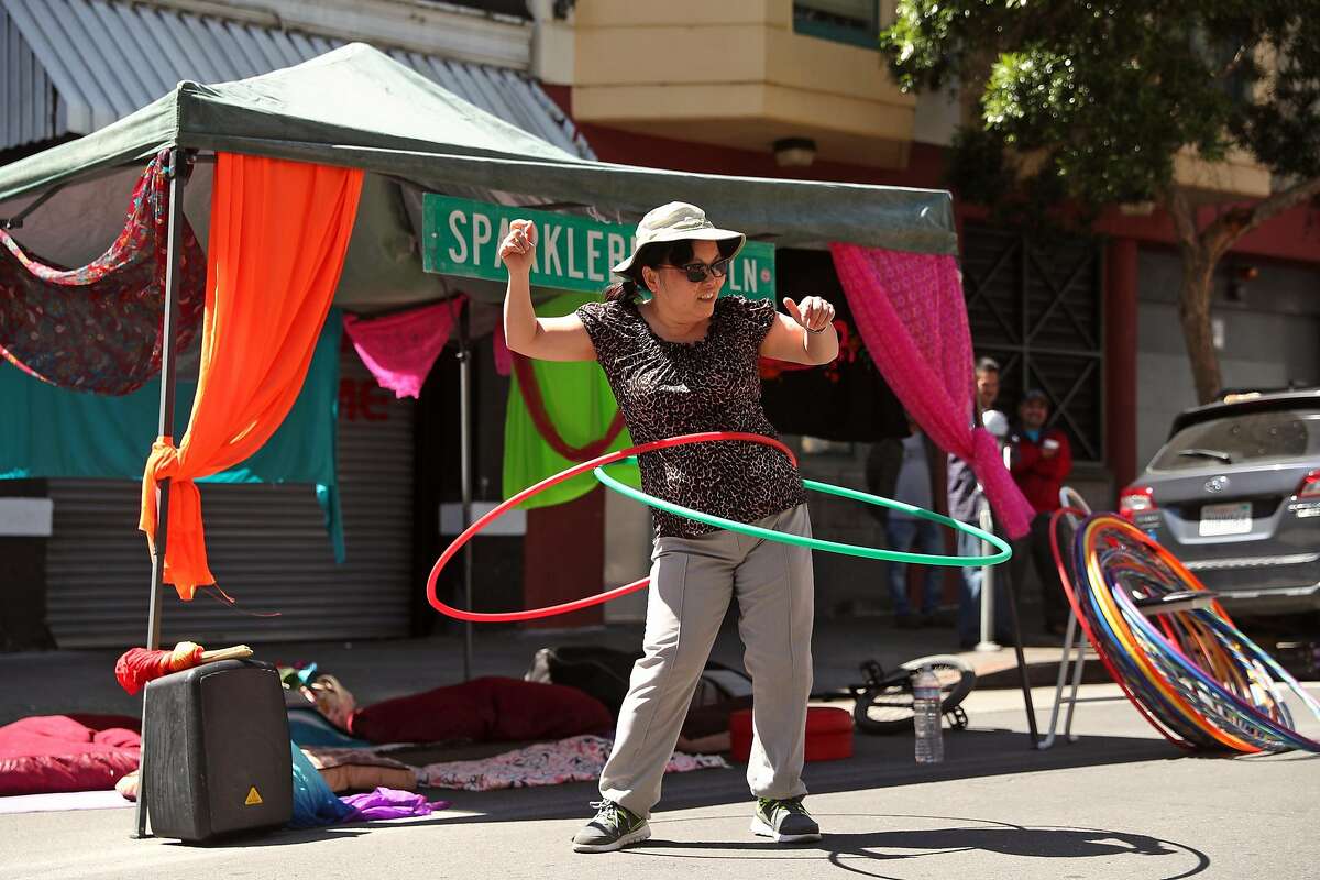 Jennifer Chung hula hoops at the "Giant Puppets Save the World" booth during Sunday Streets in The Tenderloin on Ellis Street in San Francisco, Calif., on Sunday, April 30, 2017.