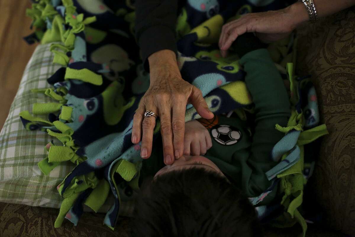 Youth care specialist Maria Vasquez tries to comfort a child on a couch in the lobby when he didn't want to sleep in his bed at The Children's Shelter in San Antonio on Dec. 22, 2016.