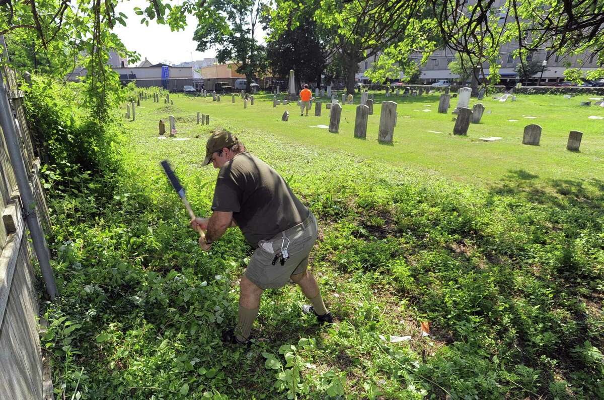 Phillip Peluso of Stamford, clears thick brush and over growth at Northfield Cemetery. Members of Greenwich's Acacia Lodge No. 85 and Stamford's Union No. 5 have been cleaning up the old burial ground at the corner of North and Franklin streets for years.