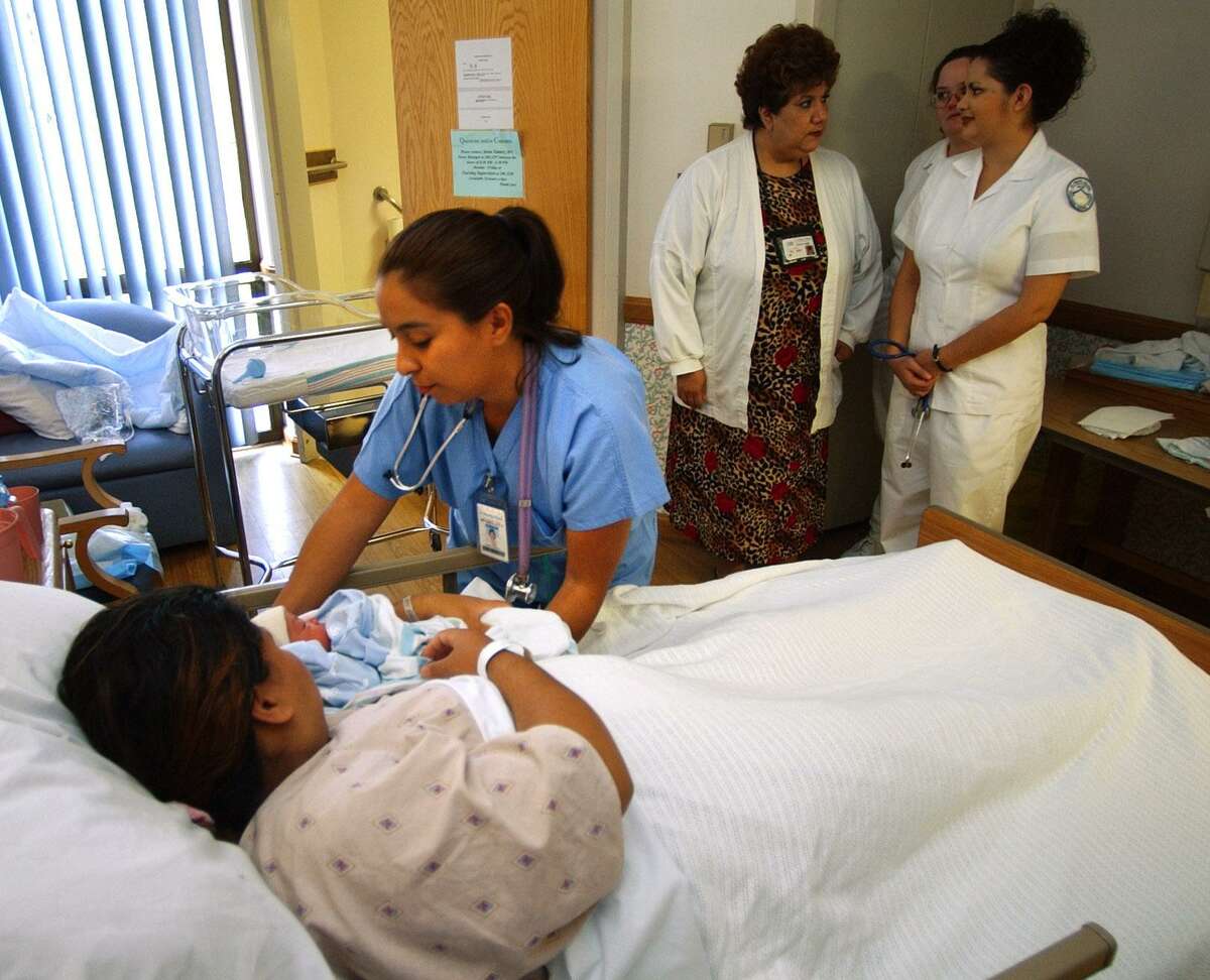 Project Quest nursing student Laura Rubio, left, works with Juanita Torres' new-born son, Jeremiah Perez, in 2001. The project, a study shows, has a deep impact on participants’ earning power.