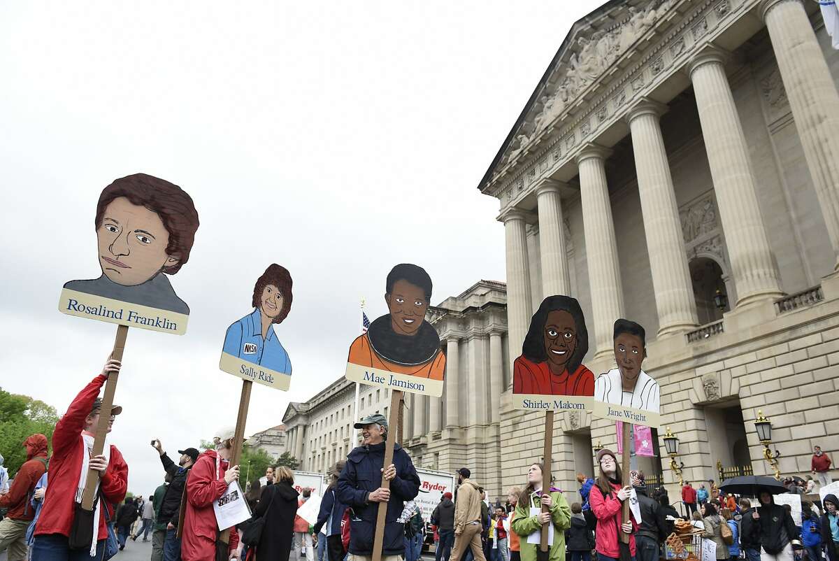 People hold signs showing women in science, in front the U.S. Environmental Protection Agency during the March for Science in Washington D.C. on April 22, 2017.
