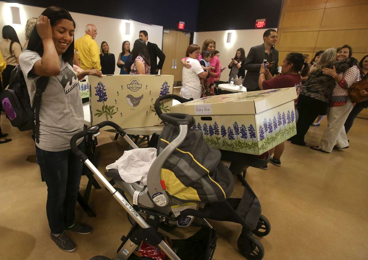 Samantha Traverzo (left) smiles at her child after receiving a new “baby box” from the Baby Box Co. on May 2, 2017, during the launch of the Baby Box University initiative at the DoSeum. About 50 of the boxes were given out to insure babies have a safe place in which to sleep. The program will provide education and distribute up to 400,000 free baby boxes in the state of Texas.