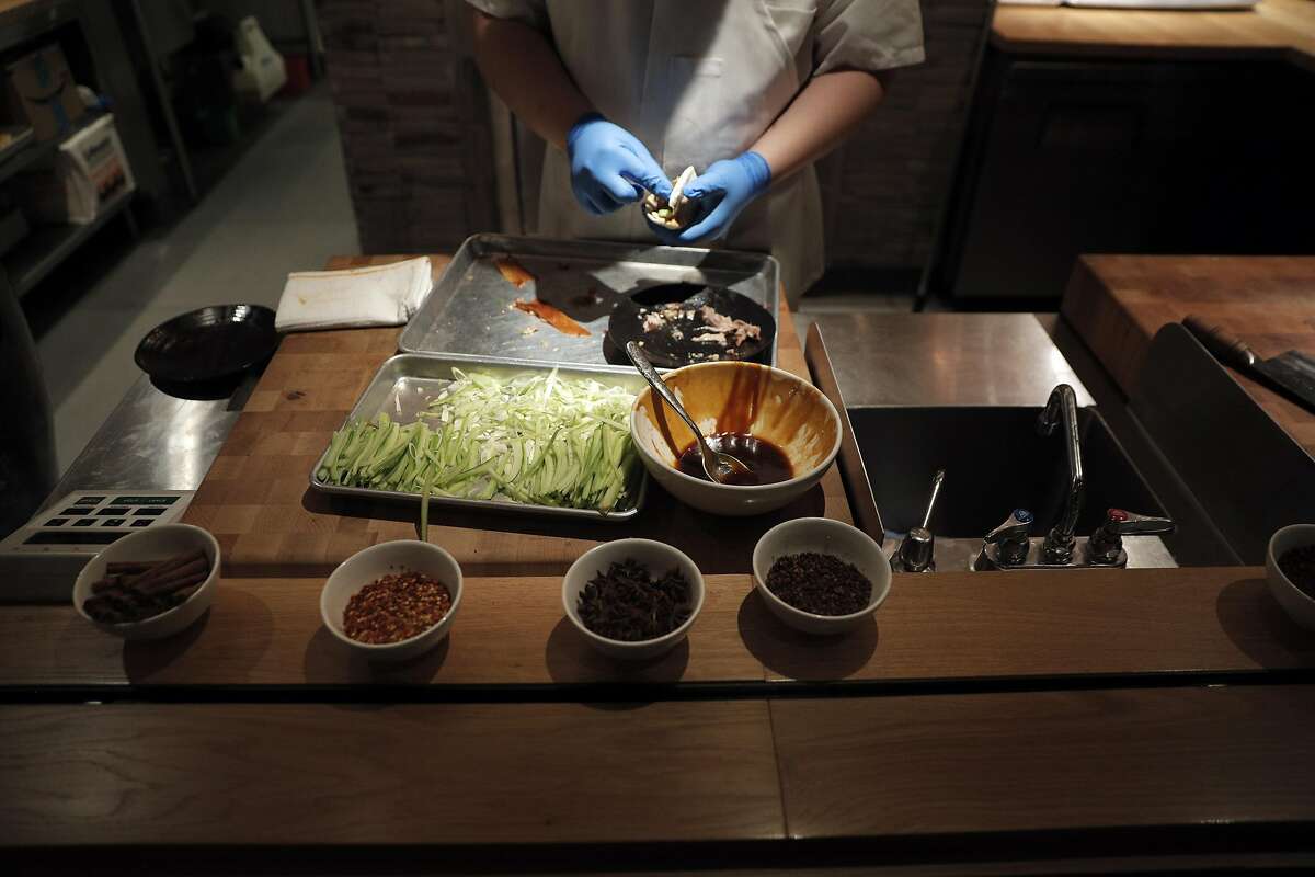 A cook prepares Peking Duck with Kumquat Glaze at the barbecue kitchen at China Live in San Francisco, Calif., on Wednesday, April 26, 2017. China Live is the new ambitious restaurant and Chinese food emporium in Chinatown.
