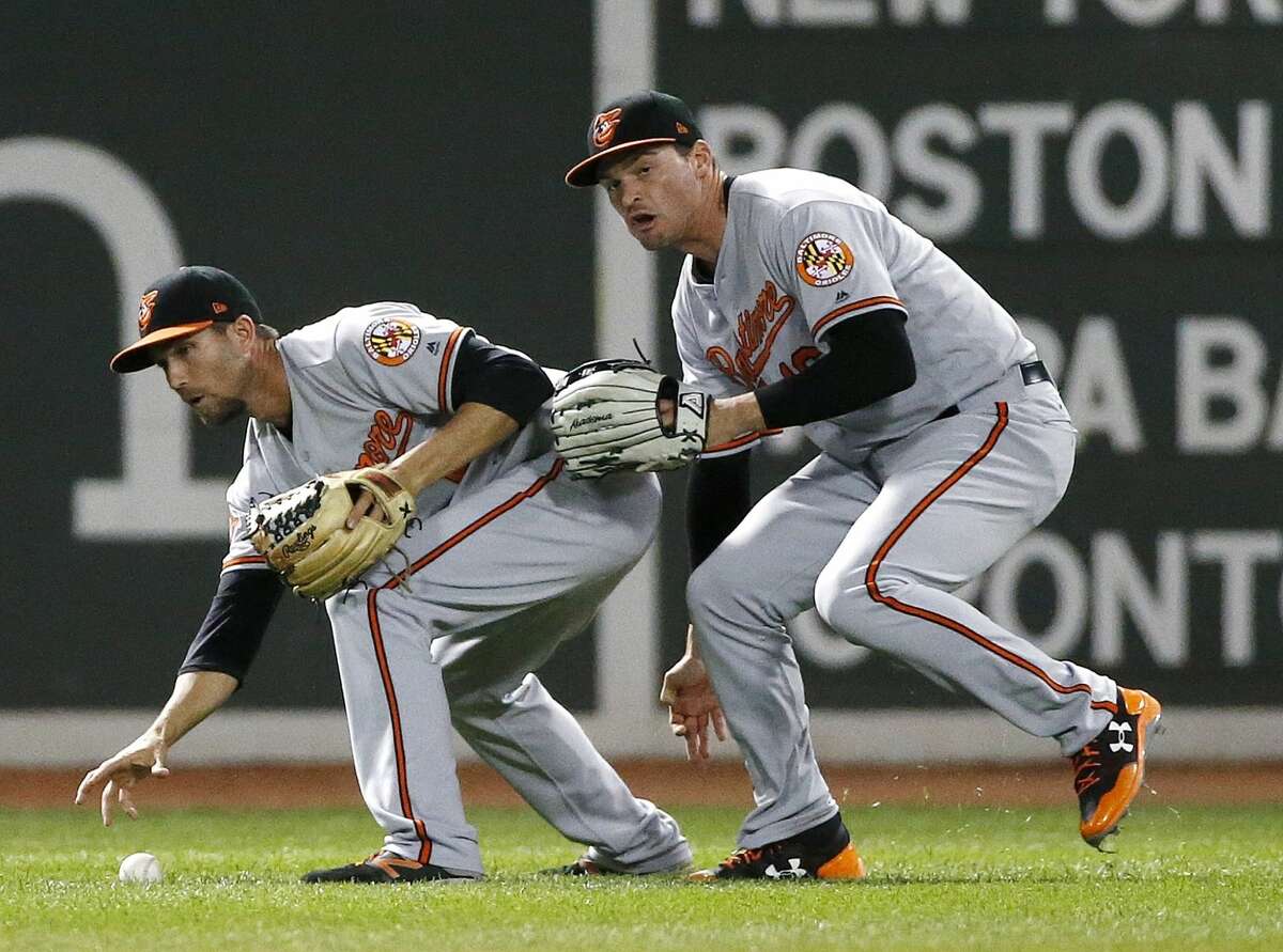 Baltimore Orioles' J.J. Hardy, left, reaches for the ball in front of Trey Mancini after failing to make the catch on a pop up by Boston Red Sox's Jackie Bradley Jr., leading to a triple play during the eighth inning of a baseball game, Tuesday, May 2, 2017, in Boston. (AP Photo/Michael Dwyer)