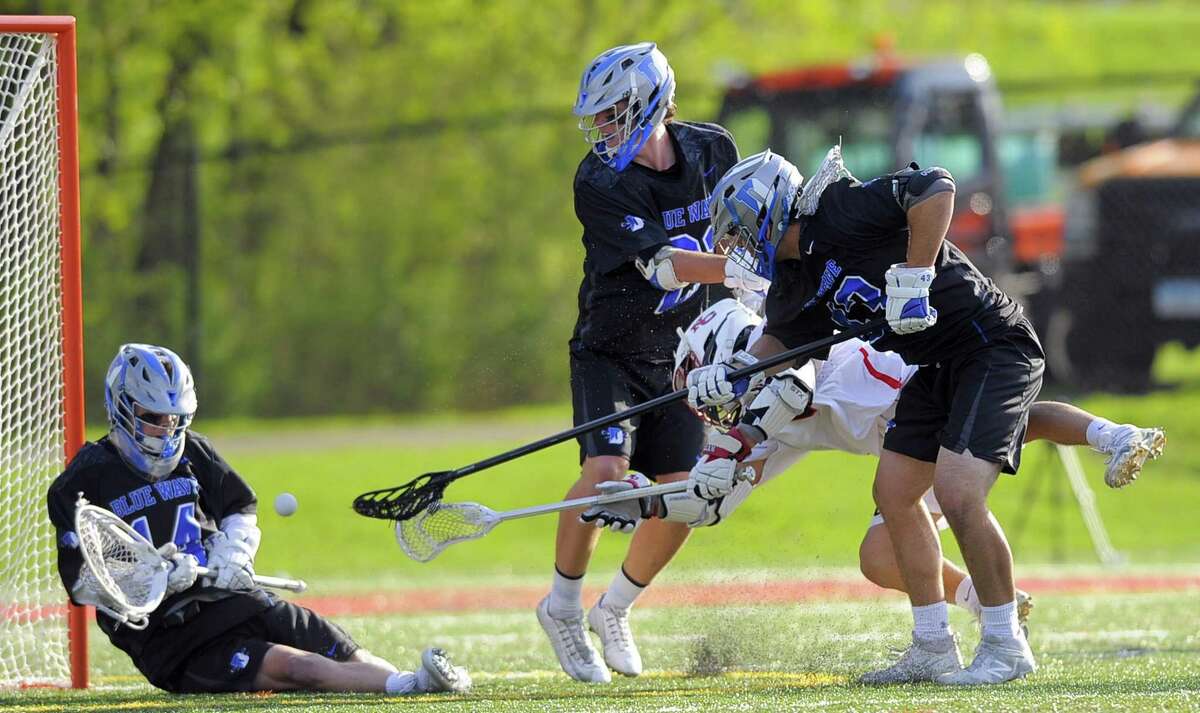 Darien goalie Ryan Cornell makes a save as New Canaan’s Jackson Appelt falls on his goal shot between Quinn Fay and Jake Bieler in a FCIAC boys lacrosse game at New Canaan High School’s Dunning Field in New Canaan on Saturday. Darien won 11-8.
