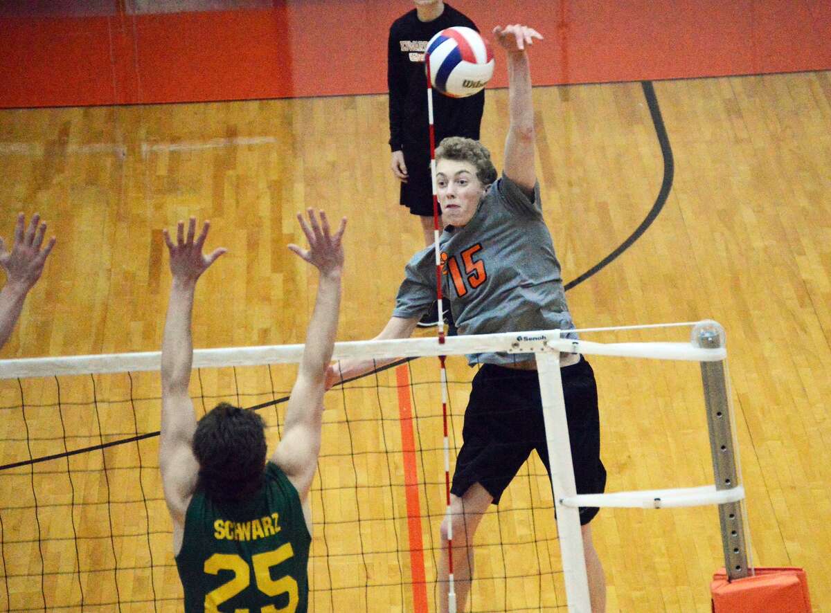 Edwardsville senior hitter Nick Allen, right, blasts a kill over the outstretched arms of Metro’s J.J. Schwarz in the first game.