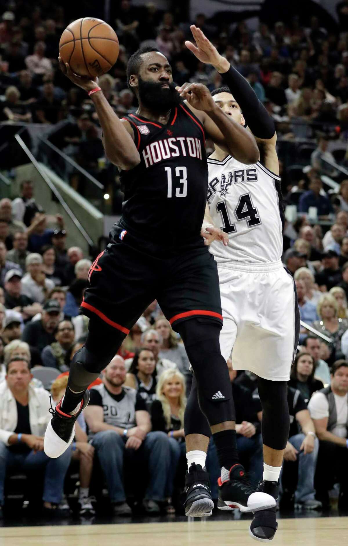 Houston Rockets guard James Harden (13) leaps to make a pass under pressure from San Antonio Spurs' Danny Green (14) during the first half of Game 2 in a second-round NBA basketball playoff series, Wednesday, May 3, 2017, in San Antonio. (AP Photo/Eric Gay)