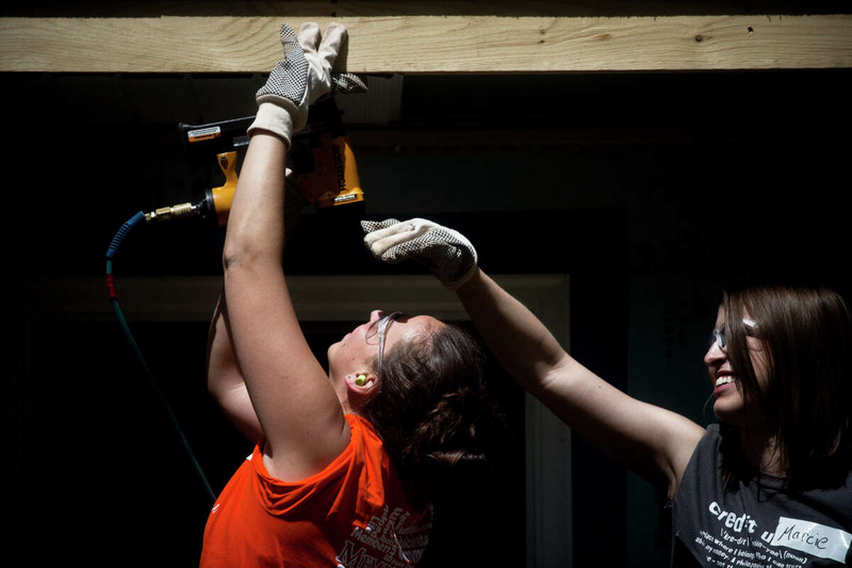 SEAN PROCTOR | sproctor@mdn.net Jayme Manderach, of Kawkawlin, works on constructing the Stillwagon's new house May 12, 2013 as Marcie Long, of Sanford, shades her eyes from the sun. Both Manderach and Long work for Members First Credit Union, and were volunteering as part of Habitat for Humanity's Women Build Week. This year's Women Build Week will start May 8.
