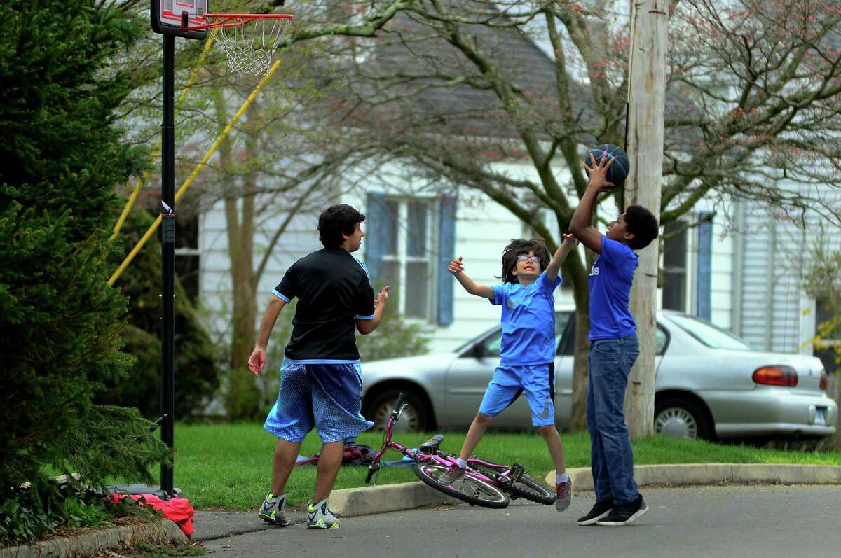 Amr Aldammad,10, in center, jumps up to try and block Branden Richardson, 13, as he attempts a shot as they play basketball with their friends on Roseville Terrace in Fairfield, Conn. on Wednesday Apr. 26, 2017.