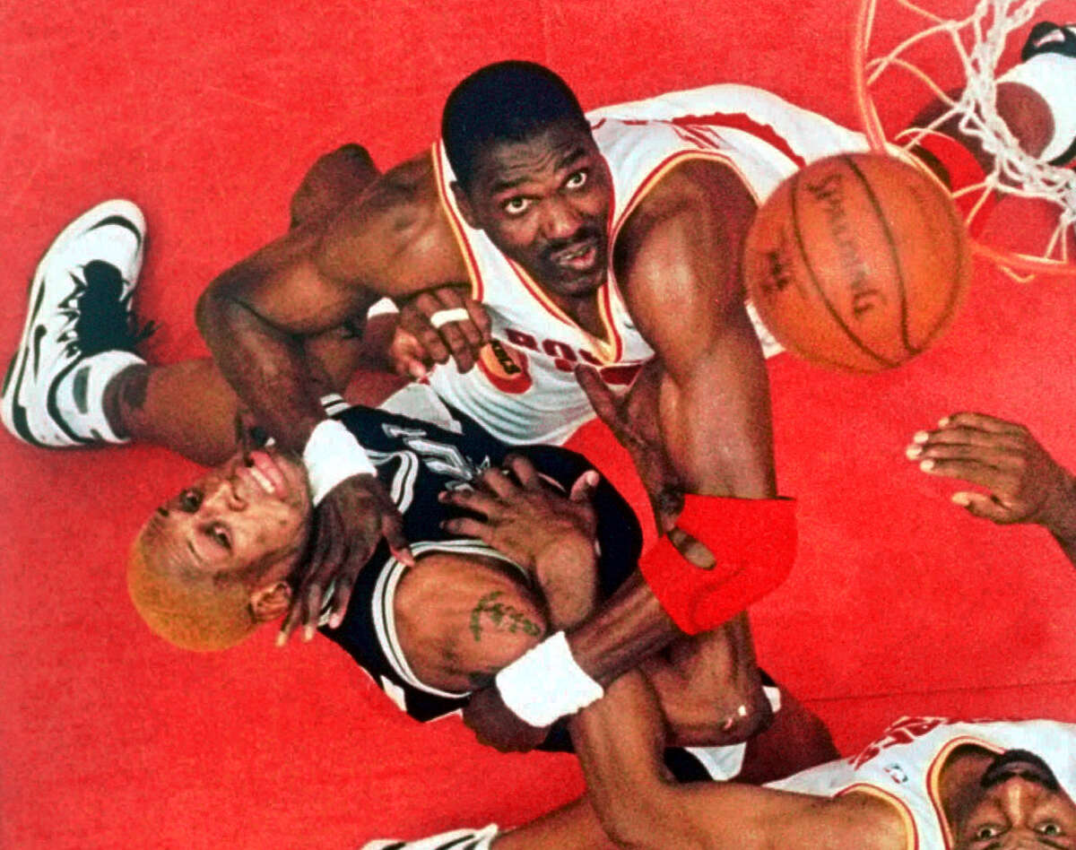 San Antonio Spurs forward Dennis Rodman, left, and Houston Rockets center Hakeem Olajuwon, top center, battle for a rebound as Houston's Charles Jones looks on at bottom right in the second quarter of their NBA Western Conference Finals game Sunday, May 28, 1995, in Houston. The final days are counting down on Hakeem Olajuwon's Houston Rockets contract, making him a free agent and possibly ending his brilliant 17-year Hall of Fame career. (AP Photo/Tim Johnson, File)