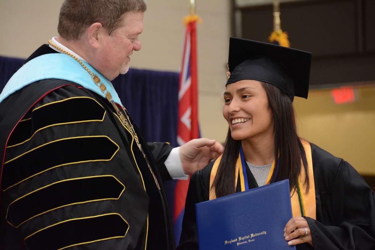 Wayland Baptist University graduating senior Mayra Ramirez of El Paso receives her diploma and congratulations from Wayland President Dr. Bobby Hall at graduation on Saturday afternoon. Ramirez, a member of the Pioneer wrestling team, served as the student speaker.