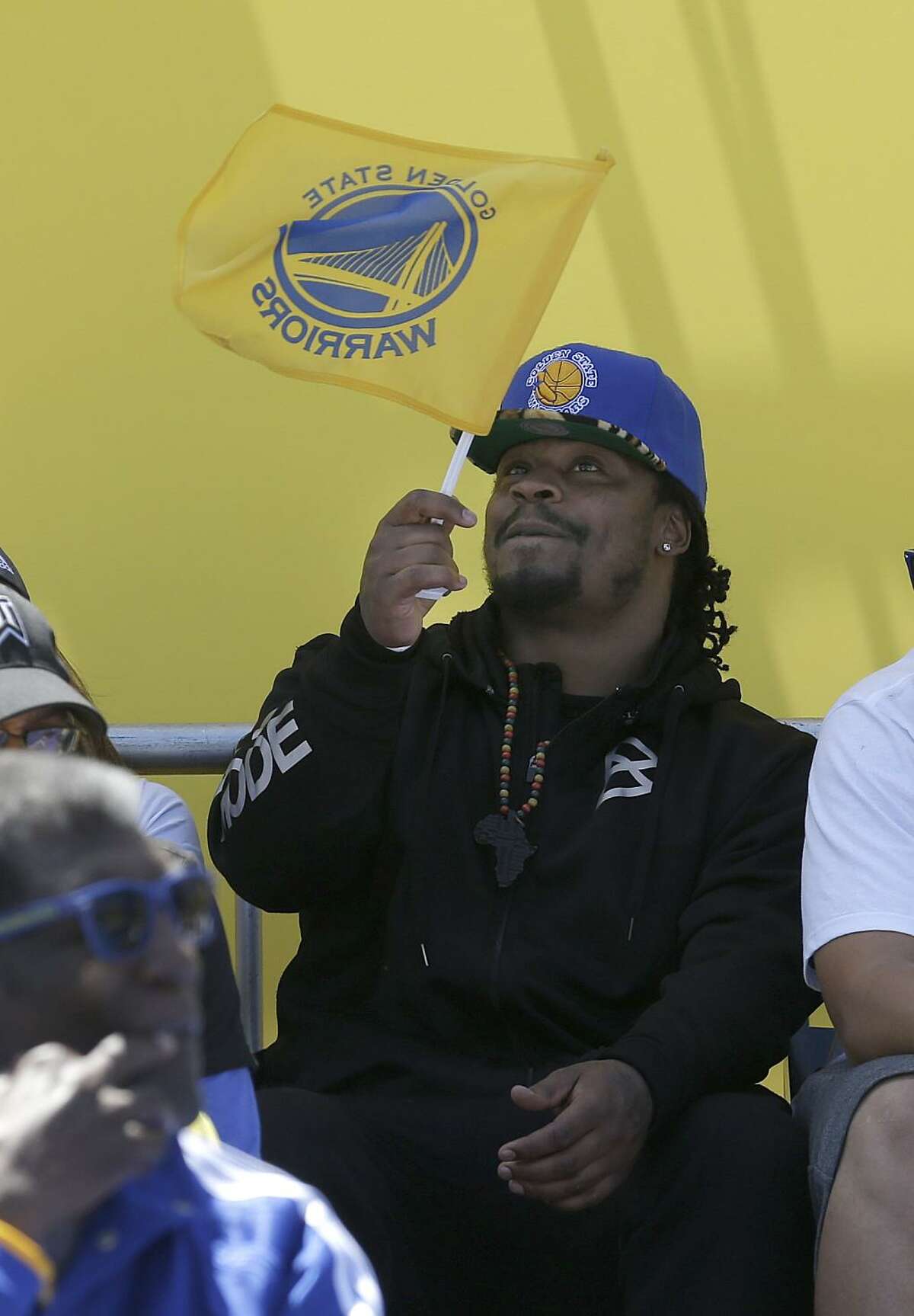 Seattle Seahawks running back Marshawn Lynch waves a Golden State Warriors flag during a rally for the Warriors winning the NBA championship in Oakland, Calif., Friday, June 19, 2015. (AP Photo/Jeff Chiu)