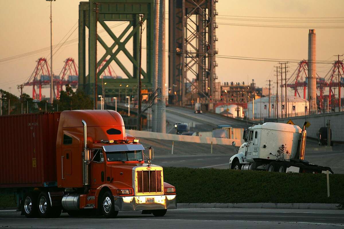 LONG BEACH, CA - JULY 06: Trucks carry shipping containers at the ports of Long Beach and Los Angeles on July 6, 2006 in Long Beach, California. In the Los Angeles area, studies indicate that diesel exhaust from trucks, locomotives, heavy equipment and ships causes cancer and is responsible for 70% of pollution-related health problems and hundreds of deaths every year. Rather than wait for the international agency that regulates the global shipping industry, the International Maritime Organization, to implement considered changes to strengthen emissions standards for cargo vessels, the ports recently unveiled an ambitious clean-air plan that could significantly improve air quality. The proposal seeks to reduce diesel emissions from cargo ships, trains and trucks by more than 50% over a five-year period at a cost of $2-billion.Almost 5,800 ships called at the ports of Los Angeles and Long Beach in 2005 released about 14,000 tons of air pollutants. Many ships emit as much exhaust per day as 12,000 cars. (Photo by David McNew/Getty Images)