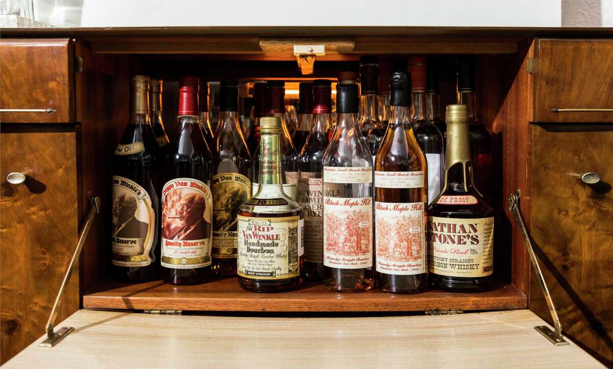 Shepherd keeps his rarest bottles of whiskey, including Pappy Van Winkle Rye, in a drop-down compartment of a mid-century bar console. 