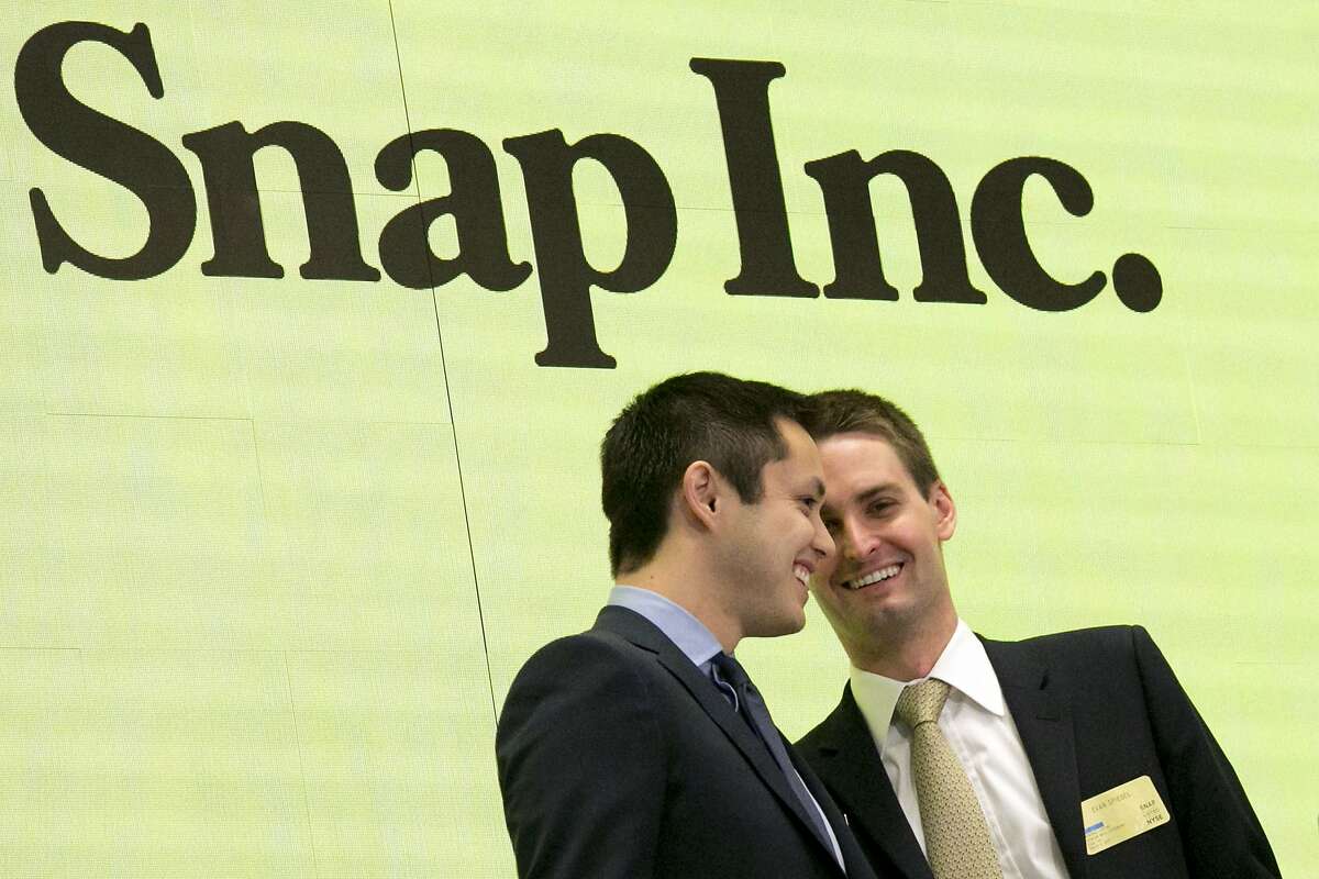 FILE - In this Thursday, March 2, 2017, file photo, Snapchat co-founders Bobby Murphy, left, and CEO Evan Spiegel ring the opening bell at the New York Stock Exchange as the company celebrates its IPO. Since it couldn’t buy its smaller rival, Facebook is bent on copying Snap to death. Snap Inc., the company behind Snapchat, meanwhile, is intent on forging ahead against its much bigger rival, courting older users, keeping young ones and along with them, advertisers. (AP Photo/Richard Drew, File)