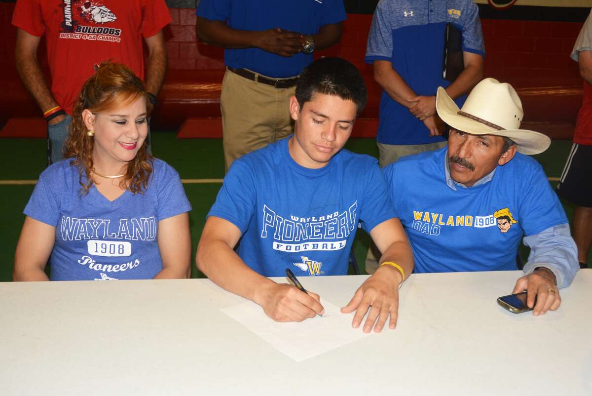 Plainview High School senior Edgar Baeza, center, signs a letter of intent to play football at Wayland Baptist University. Looking on are his mom Lucia Antu, left, and his dad Jesse Antu, right. Baeza was the Bulldogs' kicker the past two years and will play that position for the Pioneers.