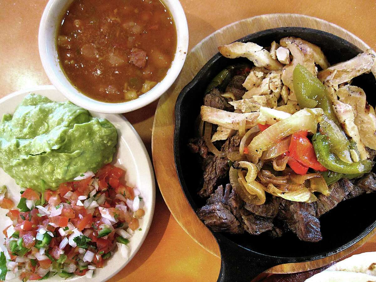 A chicken and beef fajita combo platter for one with grilled onions, guacamole, borracho beans, tortillas and pico de gallo from Don Pedro.