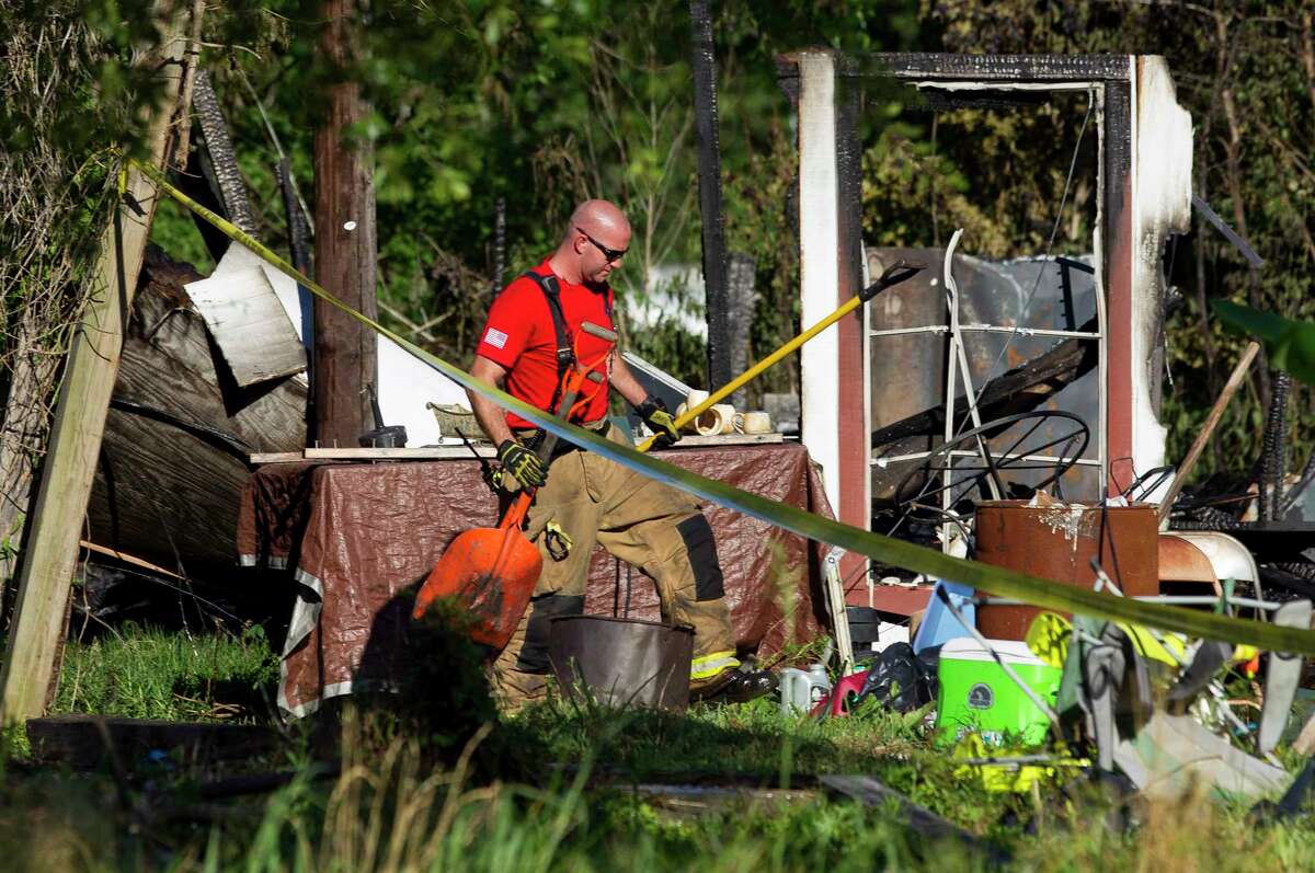 A fire fighter from The Woodlands Fire Department helps clean up debris from the scene of a house fire that killed three children between the ages of 6 and 13 on Johnson Road, Friday, May 12, 2017, in the community of Tamina, just east of The Woodlands. Five family members - a grandfather, grandmother, their son, their daughter, who was a mother of the three deceased children, and her fourth child, age 10 - were injured.