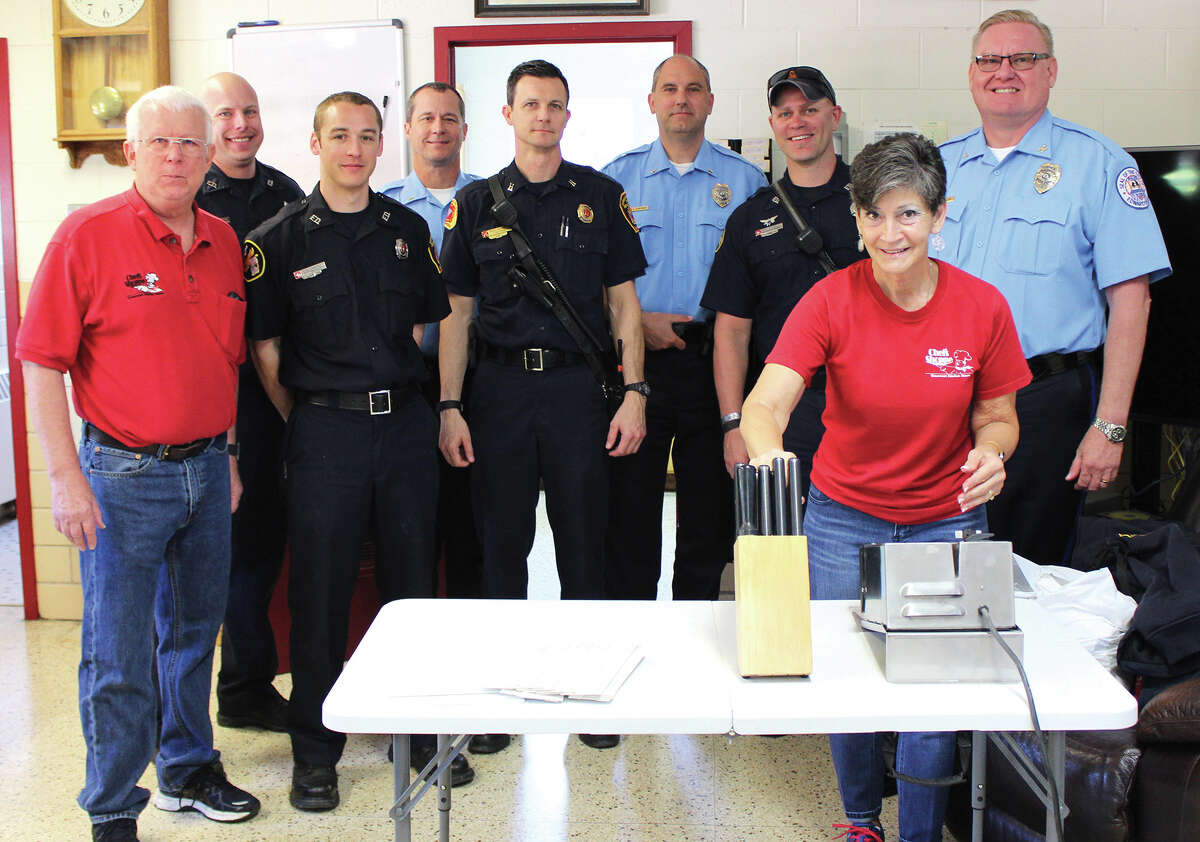 Chef’s Shoppe co-owner Scott Schneider (left) poses with employee Rolla Goff (second from right) and public safety officials after volunteering to sharpen knives for both departments Tuesday afternoon.
