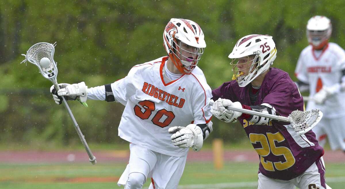Ridgefield's Harrison Cushmore (30) moves the ball behind the St Joseph goal while being defended by Colin Daly (25) in the boys lacrosse game between St Joseph and Ridgefield high schools, on Saturday afternoon, May 13, 2017, at Ridgefield High School, in Ridgefield, Conn.