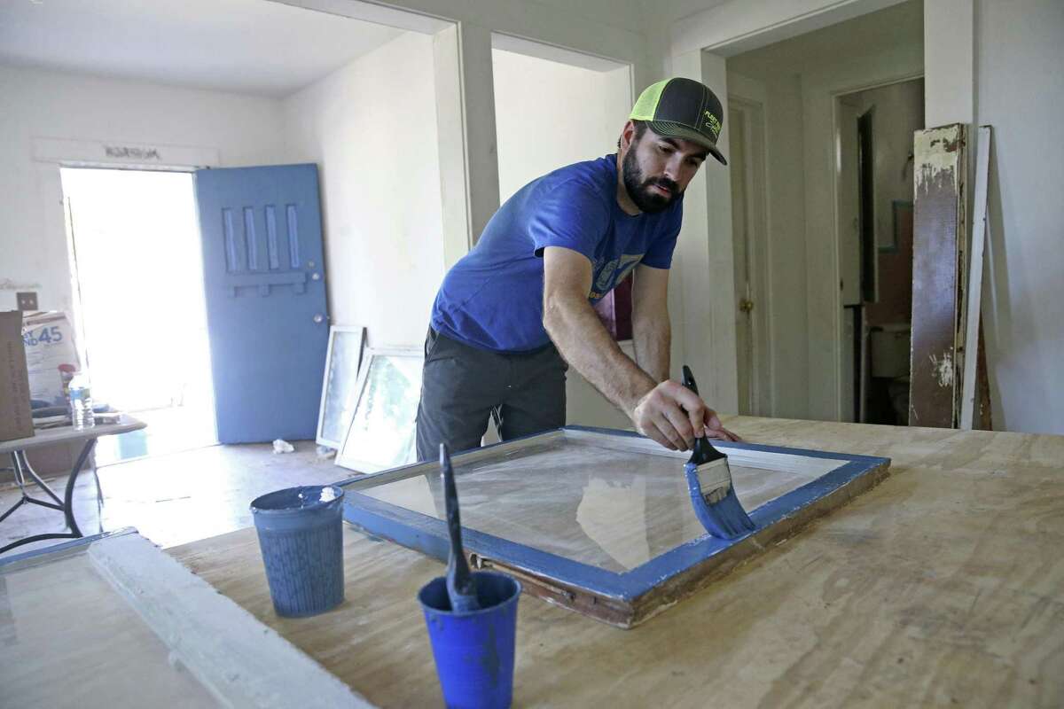 Garrett Sage, from the Office of Historic Preservation, paints window frames indoors during Rehabarama, a project to revitalize homes on two blocks of Harding place on May 13, 2017.