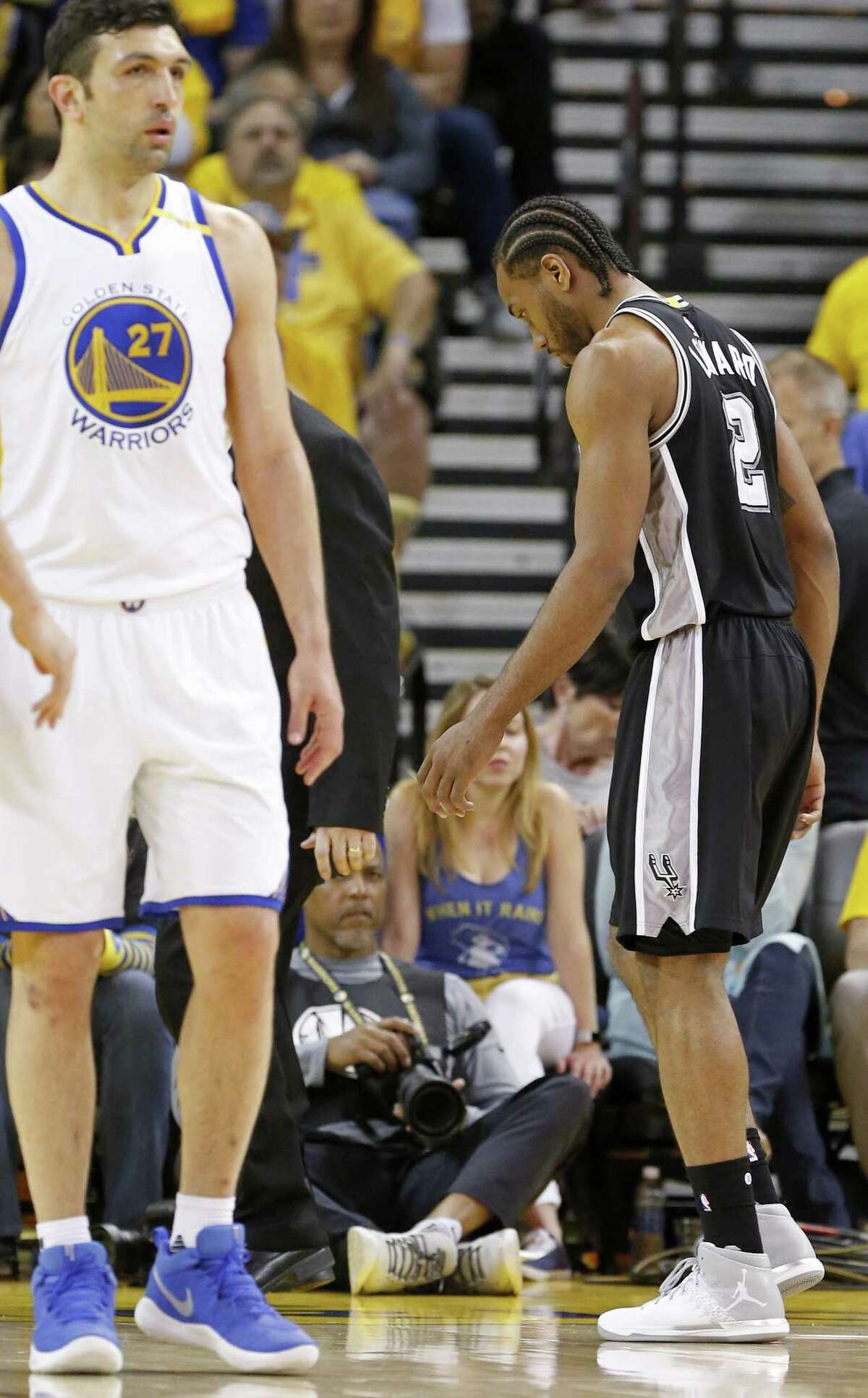 Spurs’ Kawhi Leonard walks off the court after being injured on a play involving the Warriors’ Zaza Pachulia(left) during second half action of Game 1 in the Western Conference finals on May 14, 2017 at Oracle Arena in Oakland, Calif.