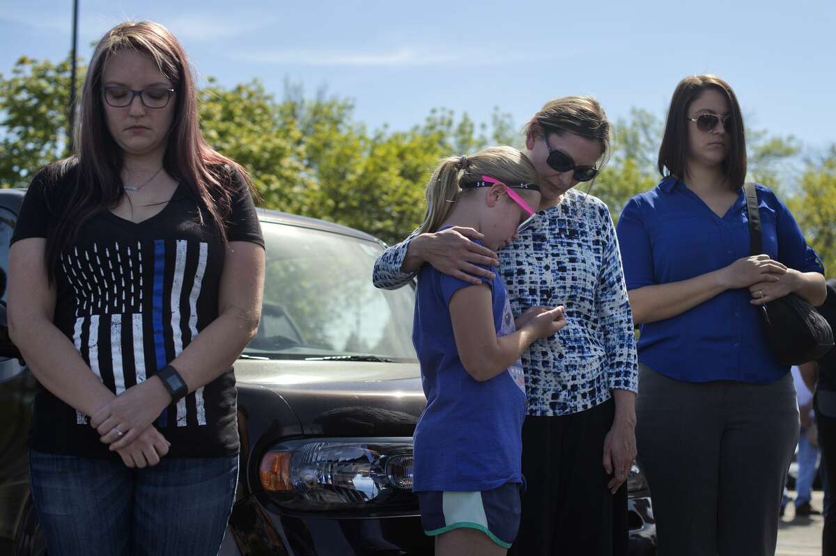 Midland residents from left: Holly McCarghar, Piper Moe, 10, Julie Moe and Savannah Crist bow their heads while listening to Rev. Wally Mayton lead police officers and people gathered at the Law Enforcement Center in prayer during a ceremony honoring National Peace Officers Memorial Day Monday afternoon.