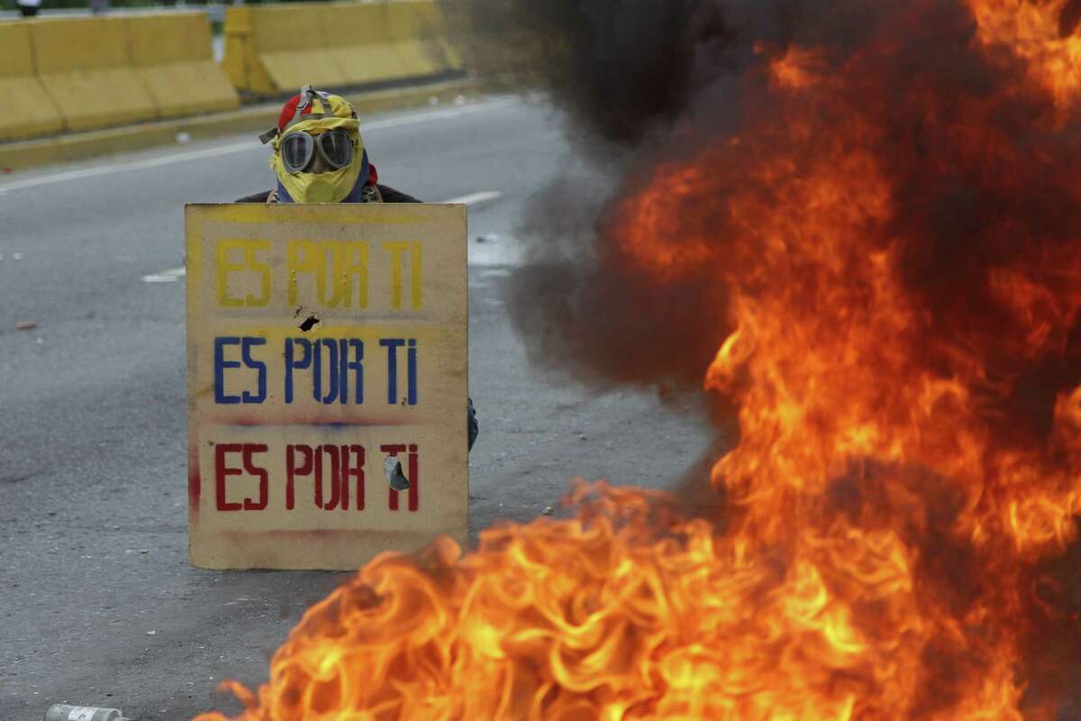 A demonstrator hols a sign that doubles a shield that reads in Spanish "It's for you," during a national sit-in against President Nicolas Maduro, in Caracas, Venezuela, Monday, May 15, 2017. Opposition leaders are demanding immediate presidential elections. (AP Photo/Ariana Cubillos)