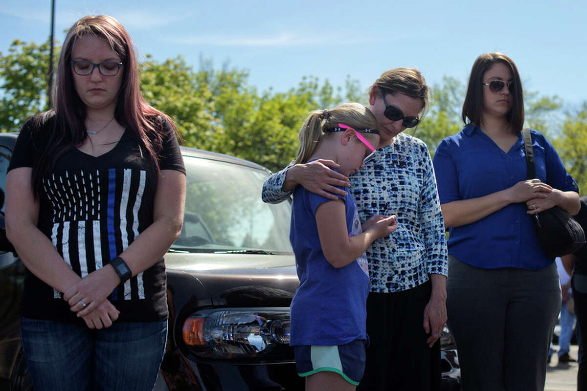 BRITTNEY LOHMILLER | blohmiller@mdn.net Midland residents from left: Holly McCarghar, Piper Moe, 10, Julie Moe and Savannah Crist bow their heads while listening to Rev. Wally Mayton lead police officers and people gathered at the Law Enforcement Center in prayer during a ceremony honoring National Peace Officers Memorial Day Monday afternoon.