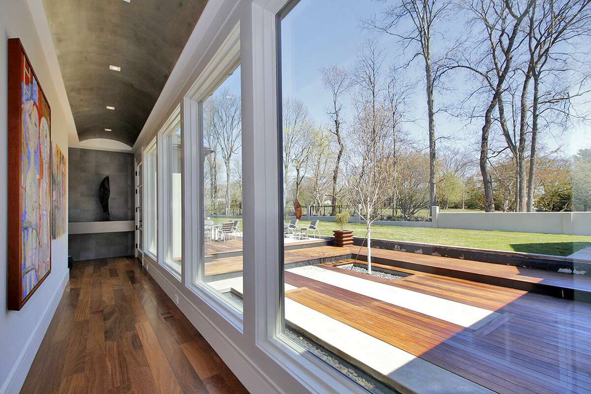 A gallery into the private master wing has floor-to-ceiling windows that look out on the 1.40-acre level property, which includes a heated in-ground salt water swimming pool, pool/guest house, three-tiered teak and limestone deck, and reflecting pool.