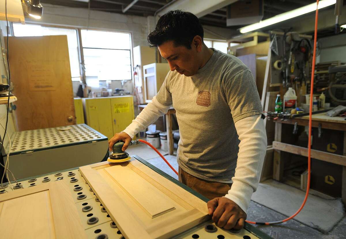 Carlos Valdiviezo sands cabinet doors at Kitchen Cabinet Resurfacing Inc.’s shop in Bridgeport.
