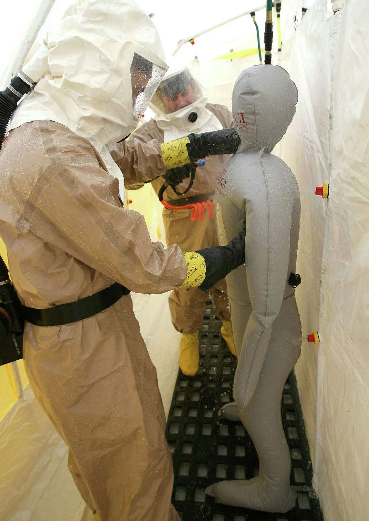 FILE - In this Friday, Nov. 4, 2011 file photo, disaster response team members Ben Olson, left, and Charles Benefield work inside a decontamination tent set up outside Banner Gateway Medical Center in Gilbert, Ariz., a suburb of Phoenix, during a state-wide drill for a nuclear disaster. The Palo Verde Nuclear Generating Station is about 50 miles west of the center of Phoenix. In changes which went into effect on December 2011, the U.S. government is allowing communities within 50 miles of nuclear power plants to practice less often for major accidents and is recommending that far fewer people who live nearby be evacuated immediately. Under new emergency planning rules, federal regulators also are ending a requirement that emergency personnel always practice for a release of radiation. (AP Photo/East Valley Tribune, Tim Hacker)