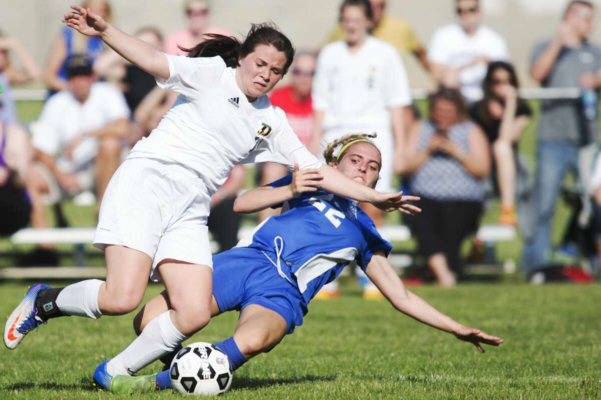 Midland's Makenzie Rajewski slide tackles Dow's Elizabeth Green in a game at Dow High School on Wednesday.