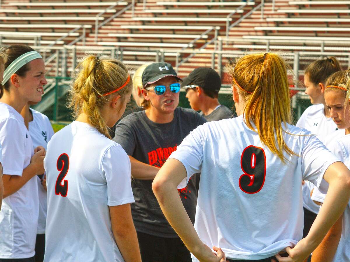 Edwardsville girls’ soccer coach Abby Comerford, center, talks to her team before the Class 3A Belleville West Regional opener against O’Fallon on Monday.