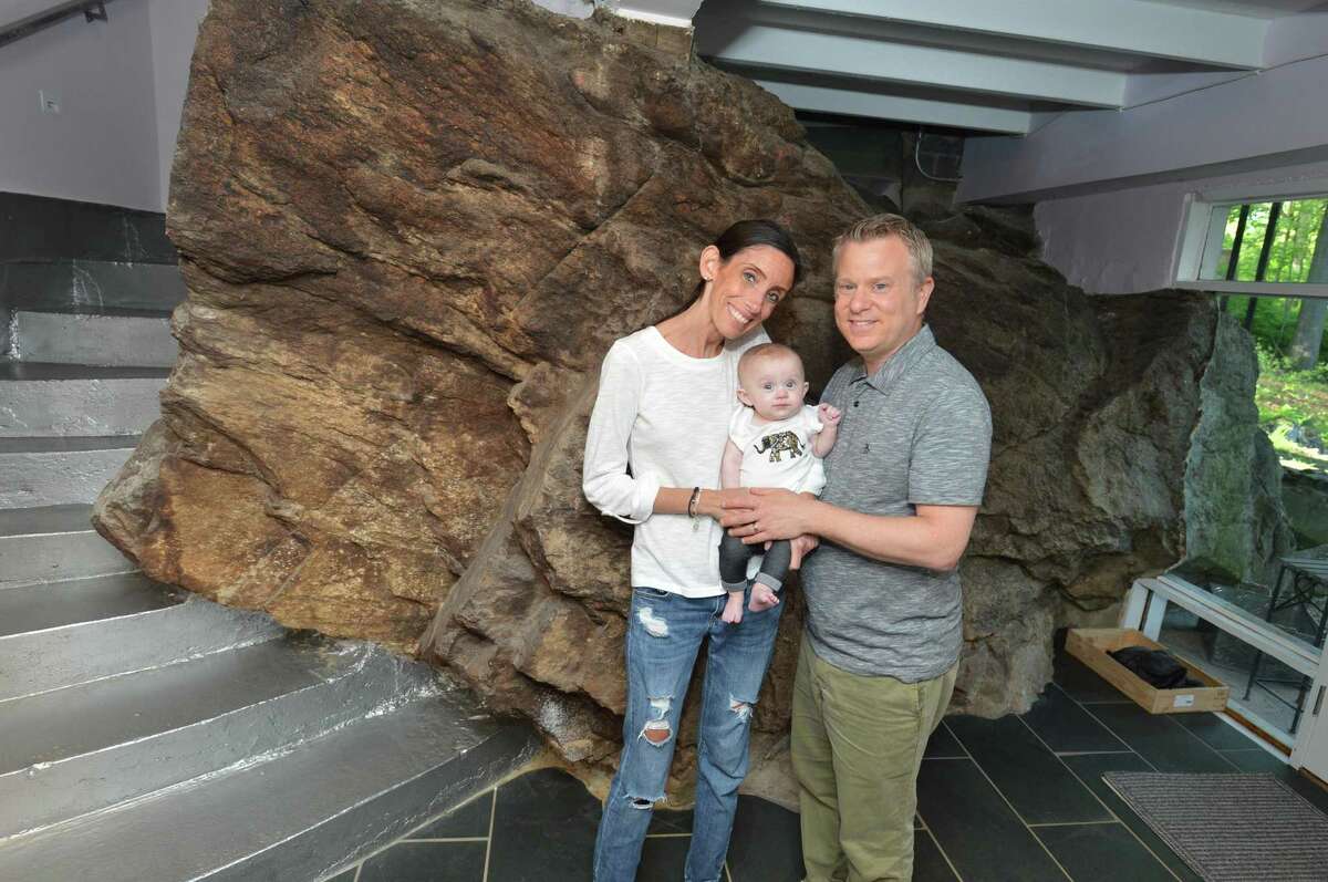 Dori and Elli Levy with daughter Harlow at the entryway to their North Seir Hill Road home alongside a boulder that is part of the outside and inside of the house in Norwalk.