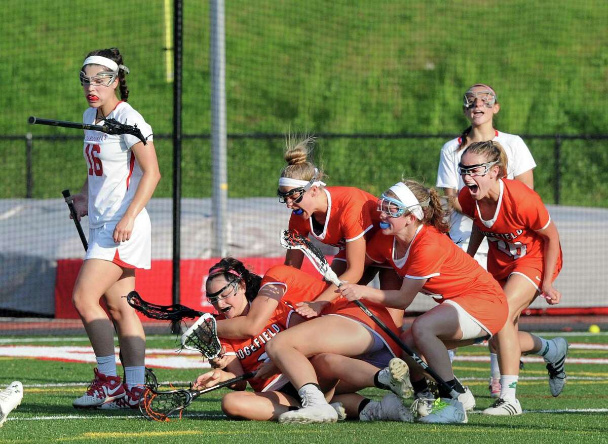 Ridgefield 's Kaitlyn McMullan, on the ground at lower left, gets dogpiled by her teammates after scoring the winning goal in the second overtime period during the girls FCIAC high school lacrosse playoff game between Greenwich High School and Ridgefield High School at Greenwich, Conn., Thursday, May 18, 2017. At left for Greenwich walking off the field is Olivia Caan (16). Ridgefield advanced winning the match 15-14 on McMullan's goal.
