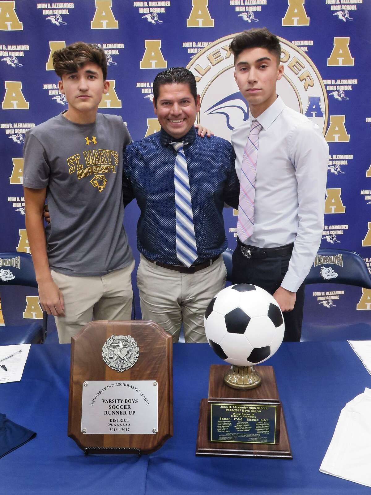 Alexander soccer head coach Danny Hermosillo, center, celebrated with Max De Leon, left, and Victor Ayala as the two signed their national letters of intent to continue their athletic carrers. De Leon signed with St. Mary’s while Ayala inked with TAMIU.