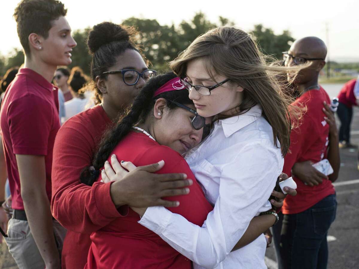 Seniors Alexandria Allen (from left in the foreground), Ana Moreno and Emily Eck hug one another during Thursday’s vigil.
