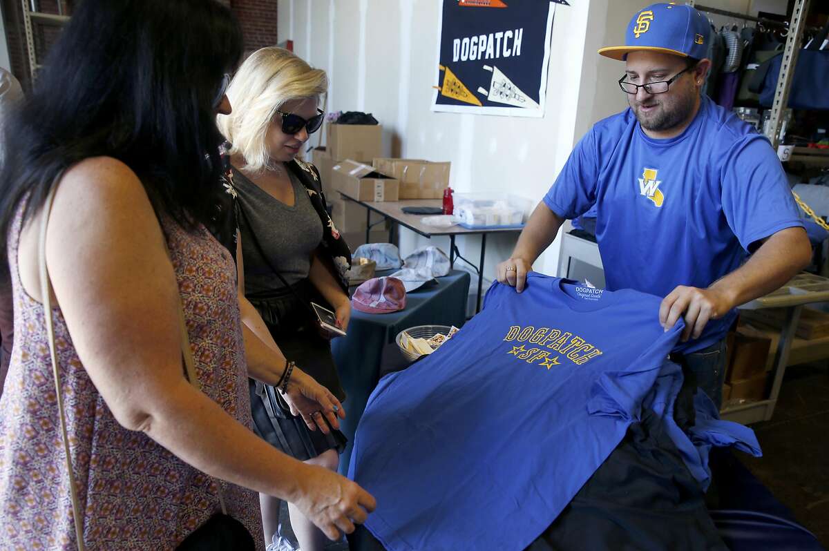 Carlos Godinez sells shirts displaying community pride to JoAnn Barrett (left) and her daughter-in-law Loni Venti at Rickshaw Bagworks during a Dogpatch neighborhood block party in San Francisco, Calif. on Saturday, May 20, 2017.