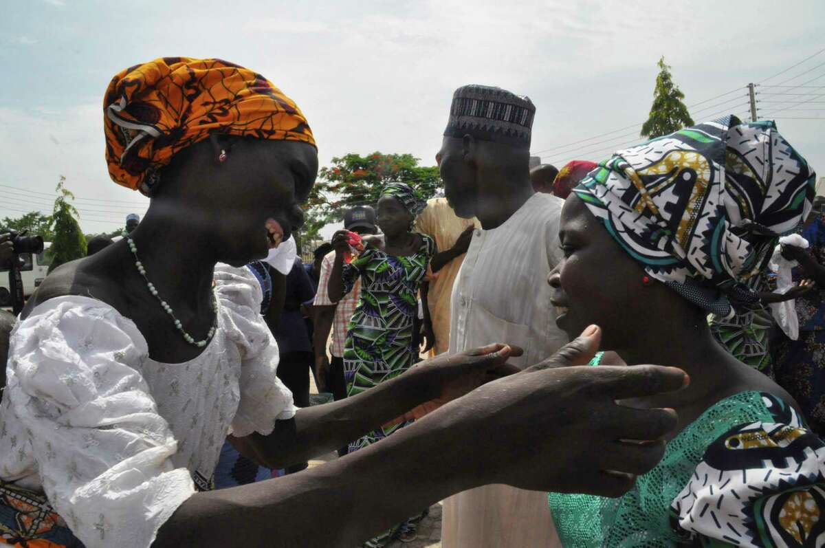 Family members celebrate as they embrace a relative, one of the released kidnapped schoolgirls, in Abuja, Nigeria, Saturday, May 20, 2017. ?The 82 Nigerian schoolgirls recently released after more than three years in Boko Haram captivity reunited with their families for the first time Saturday, as anxious parents looked for signs of how deeply the extremists had changed their daughters' lives. (AP Photo/Olamikan Gbemiga)