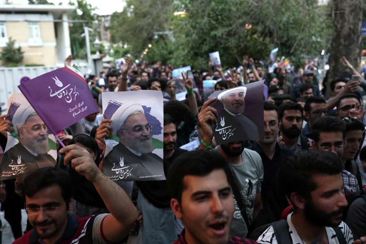 Supporters of newly re-elected Iranian President Hassan Rouhani take to the streets to celebrate his victory in downtown Tehran Saturday. Iran's president oversees a vast state bureaucracy employing more than 2 million people.﻿