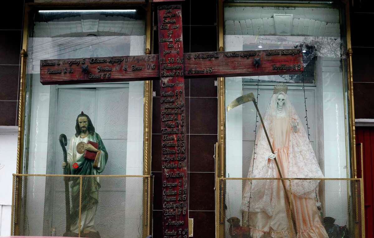 A statue of Saint Judas Thaddeus, left, stands next to the Death Saint, or "Santa Muerte," inside niches at Mercy Church on the edge of Mexico City's Tepito neighborhood.