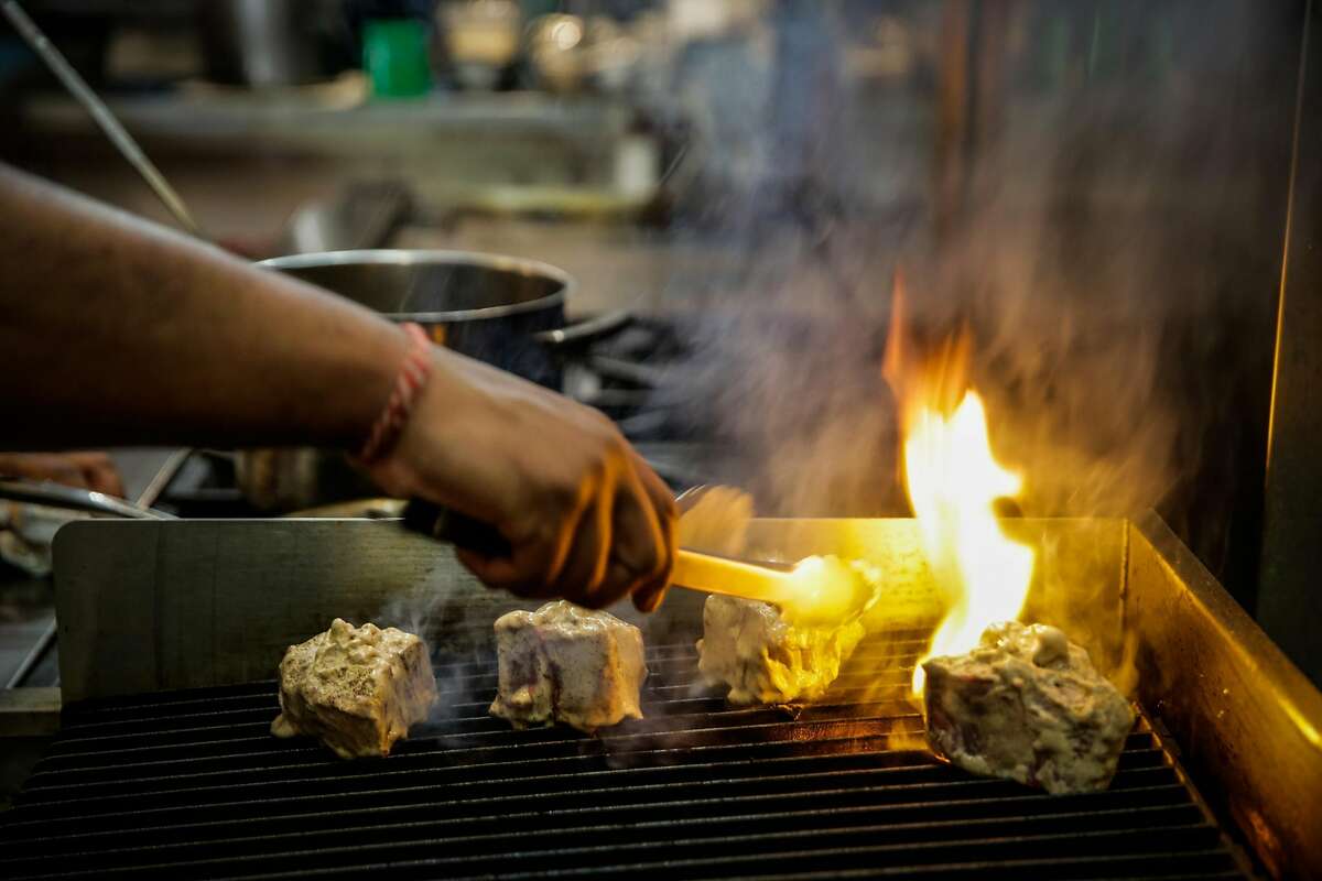 Chef Rupam Bhagat turns over a piece of lamb meat while preparing a lamb dish on the grill at Dum Indian Restaurant in San Francisco, California, on Monday, May 8, 2017.