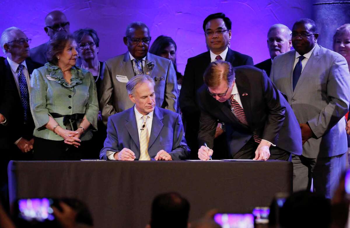Lt. Governor Dan Patrick signs the bill as Governor Greg Abbott looks on during the SB 24 signing ceremony during the 11:00 am worship service at Grace Church, The Woodlands on Sunday, May 21, 2017.
