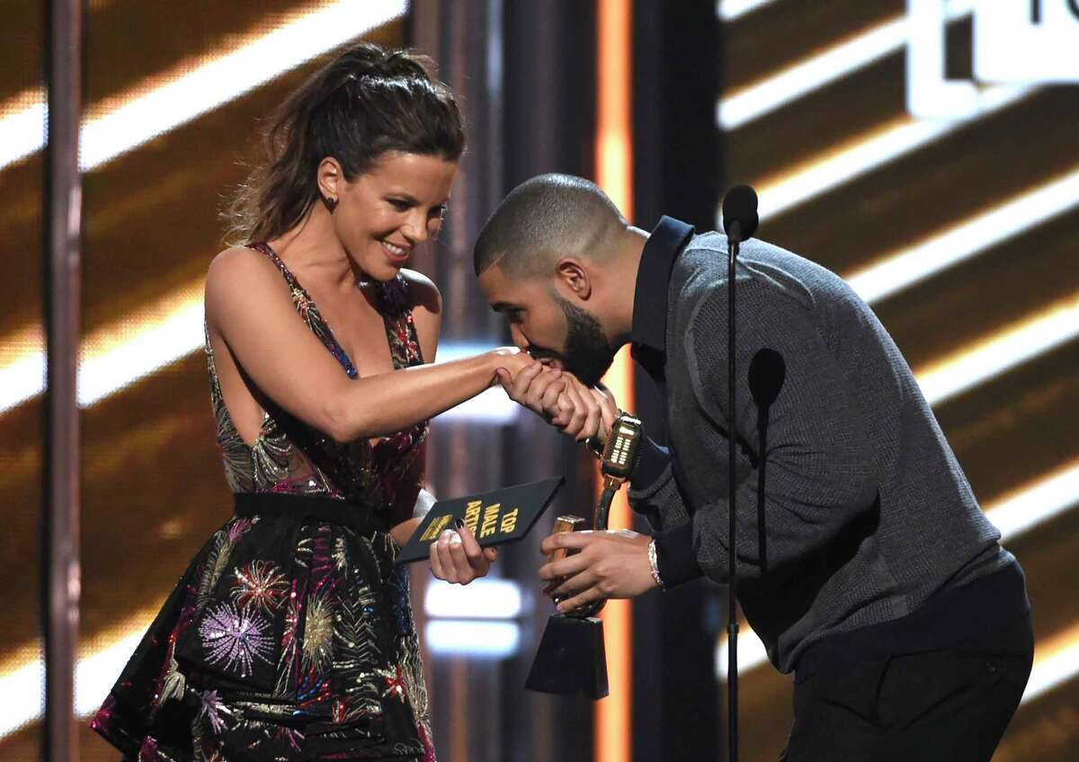 Drake kisses presenter Kate Beckinsale as he accepts the trophy for top male artist, one of a dozen Billboard Music Awards he won.