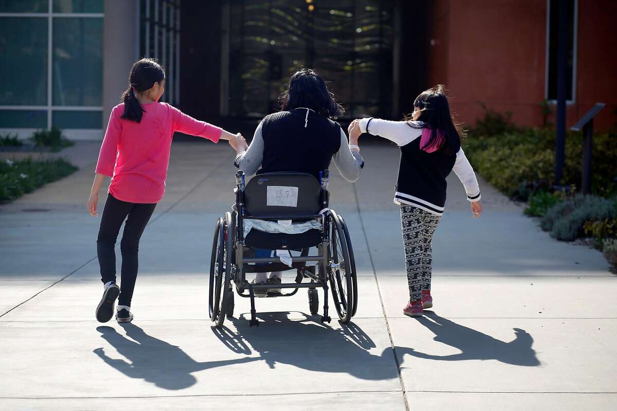 Emma Zhou (center) holds the hands of her daughters as they pull her toward an entrance at Laguna Honda Hospital and Rehabilitation Center after visiting the Virginia Leishman Farm during a visit with their mother during their spring break on Thursday, March 30, 2017 in San Francisco, Calif.