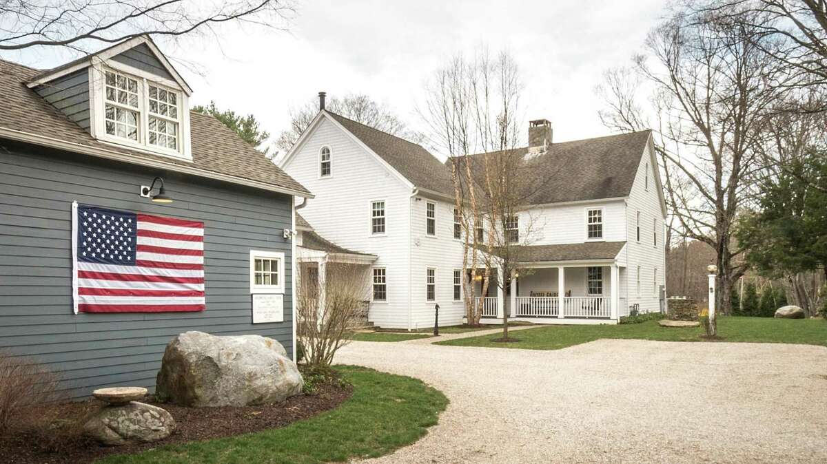 An American flag is displayed on the guest cottage of the updated vintage colonial farmhouse at 3808 Redding Road in Fairfield, a property that has more than 16 acres of land, a barn and other agricultural amenities.
