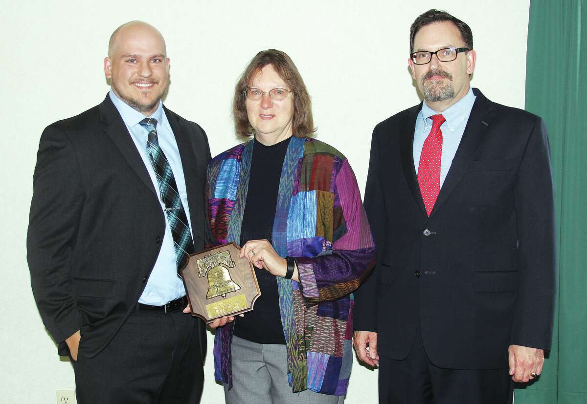 From left, Aaron and Judy Grigg accepted the Liberty Bell Award on behalf of Robert L. Grigg who was this year’s recipient. Dallas Rooney, president of the Huron County Bar Association, presented the plaque to the duo recently at a luncheon honoring the late Bad Axe teacher.