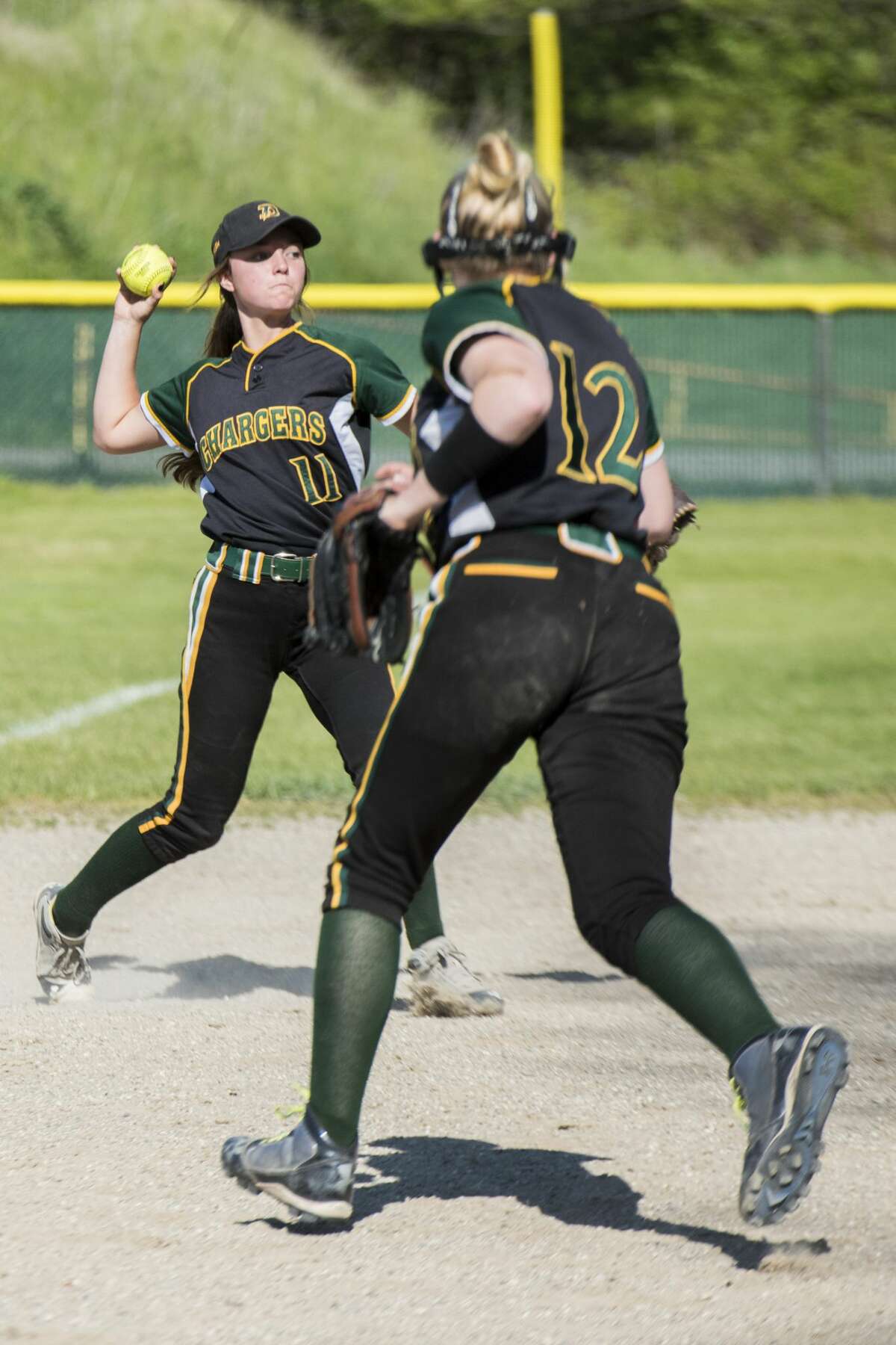 Dow senior Kylee Alexander fields the ball as pitcher, sophomore Riley Davis, watches during a double-header at H.H Dow High School in Midland on Monday.