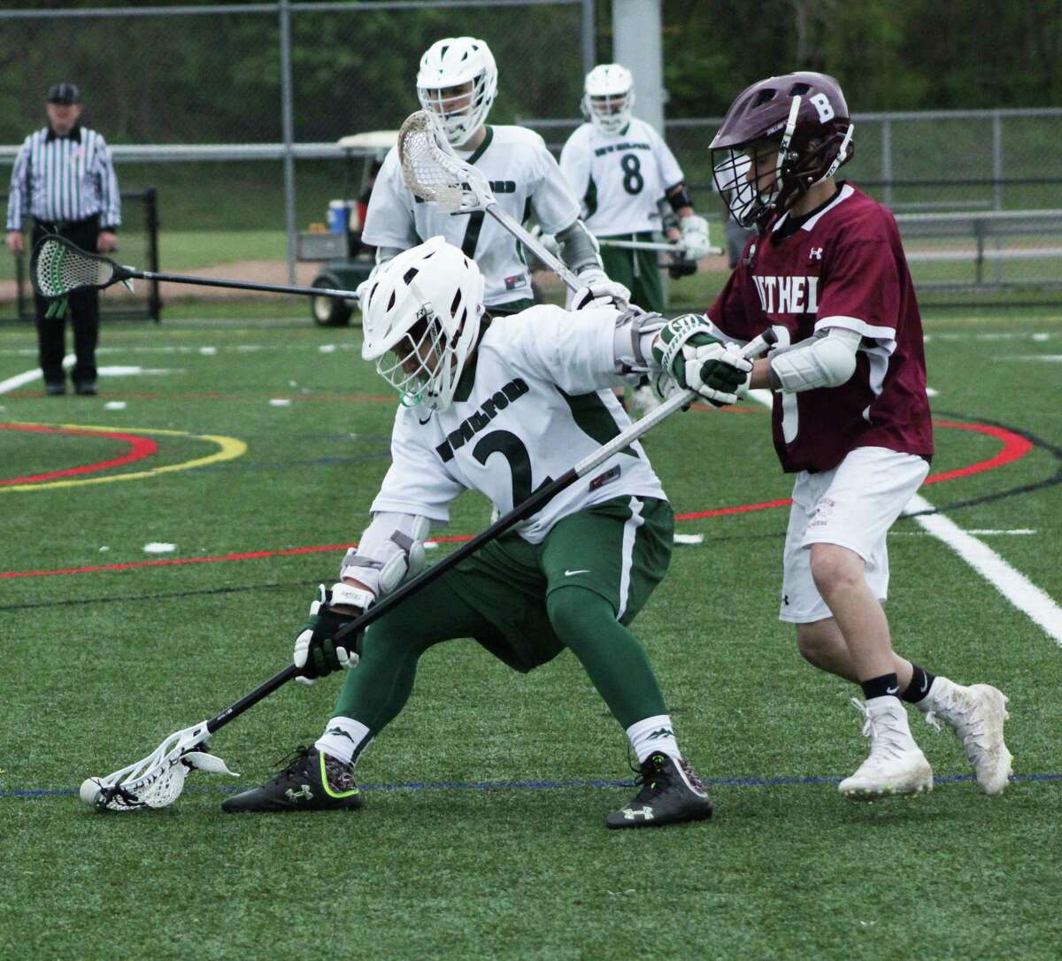 The New Milford High School varsity lacrosse faced off against Bethel May 9. Green Wave won the game 16-2. Above, sophomore Devin Cera holds off his Bethel opponent to scoop the ball.